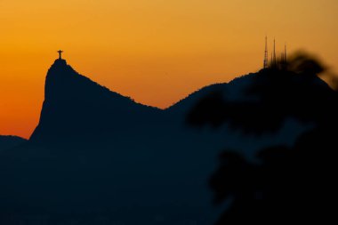 Cristo Redentor gün batımında, turuncu gökyüzü ile, Rio de Janeiro, Brezilya