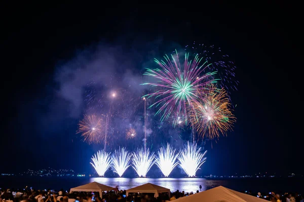 Night images of the arrival of the New Year (Reveillon). Event with party, concerts and fireworks. People observe the lights and colors of the explosions on a beach in Rio de Janeiro, Brazil