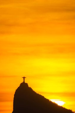 Rio de Janeiro, Brezilya: 2021 - Cristo Redentor 'un (Kurtarıcı İsa) açık turuncu gökyüzü ile günbatımında geniş bir görüntüsü