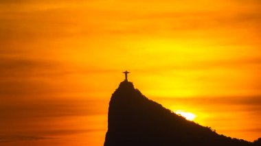 Rio de Janeiro, Brezilya: 2021 - Cristo Redentor 'un (Kurtarıcı İsa) açık turuncu gökyüzü ile günbatımında geniş bir görüntüsü