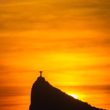 Rio de Janeiro, Brezilya: 2021 - Cristo Redentor 'un (Kurtarıcı İsa) açık turuncu gökyüzü ile günbatımında geniş bir görüntüsü