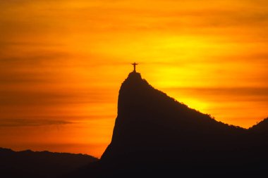 Rio de Janeiro, Brezilya: 2021 - Cristo Redentor 'un (Kurtarıcı İsa) açık turuncu gökyüzü ile günbatımında geniş bir görüntüsü