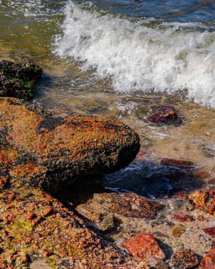 Gün boyunca plajda kaya oluşumlarının (taşlar) dokusu ve keskinliğiyle görüntüsü