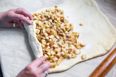 Kadınlar elmalı turta için elmaları üzümle şekillendiriyor. Turta elma ve kuru üzümle doluyor. Turta için maya hamuru.