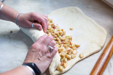 Kadınlar elmalı turta için elmaları üzümle şekillendiriyor. Turta elma ve kuru üzümle doluyor. Turta için maya hamuru.