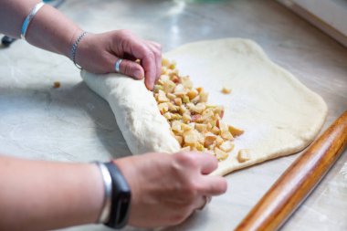 Kadınlar elmalı turta için elmaları üzümle şekillendiriyor. Turta elma ve kuru üzümle doluyor. Turta için maya hamuru.