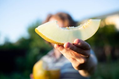 Erkek (erkek) ellerindeki kavun dilimleri insanın önünde. Kavun ellerinde ve yaz ışığı var. Bahçede yetişen kavun