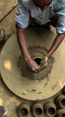 Indian potter crafting pots by hands-on spinning potters wheel.