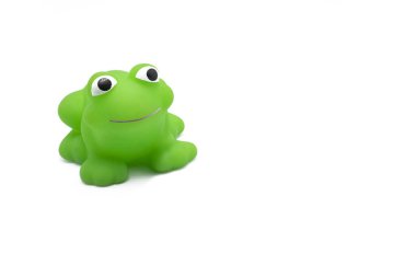 Beyaz arka planda gülümseyen yeşil plastik kurbağa oyuncağı.
