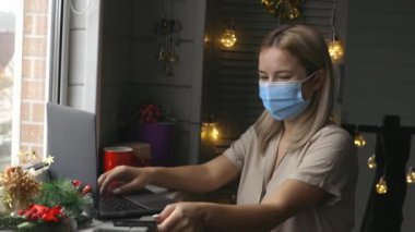 Koruyucu maskeli mutlu bir kadın, karantina süresince evde online alışveriş yapıyor ve karantina sırasında Noel hediyesi alıyor.. 