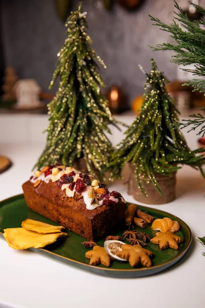Christmas poppy seed cake covered with icing and decorated with raisins and walnuts on the holiday table. — Zdjęcie stockowe