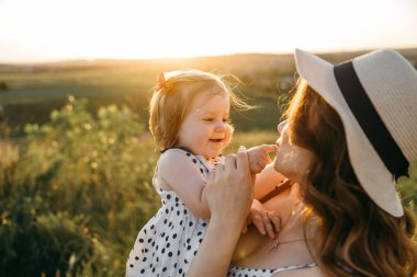 Anne gün batımına karşı kızının parmağını nazikçe öper.