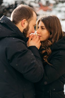 Bir adam soğuk havada sevgilisinin ellerini nazikçe ısıtır.