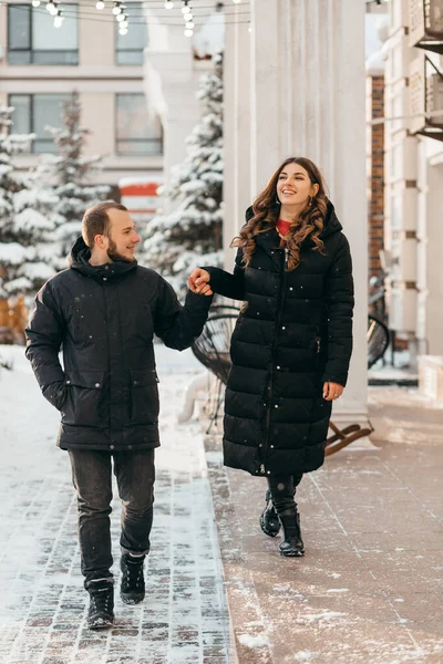 Una pareja enamorada pasea por la ciudad nevada cogida de la mano — Foto de Stock