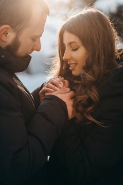 Bir adam soğuk havada sevgilisinin ellerini nazikçe ısıtır.