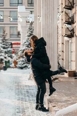 Sevgi dolu ve mutlu bir adam kız arkadaşını kollarında tutuyor.