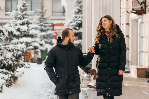 Una pareja enamorada pasea por la ciudad nevada cogida de la mano — Foto de Stock