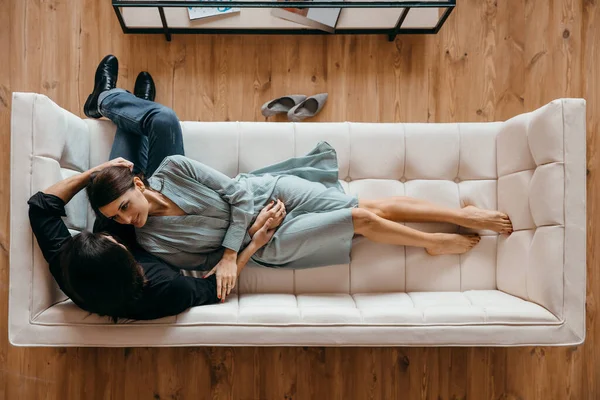 Det unga paret kopplar av i en lyxig vit soffa. Utsikt ovanifrån. — Stockfoto