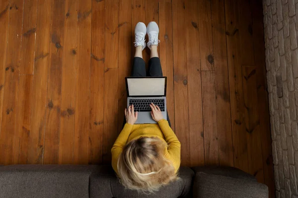 Молода жінка працює на сучасному ноутбуці, сидячи на підлозі вдома. Вид зверху — стокове фото
