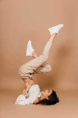 Pastel arka plan üzerinde kaldırılmış bacaklarla yerde yatan mutlu, sıradan bir kadın. Bayan, sevimli..