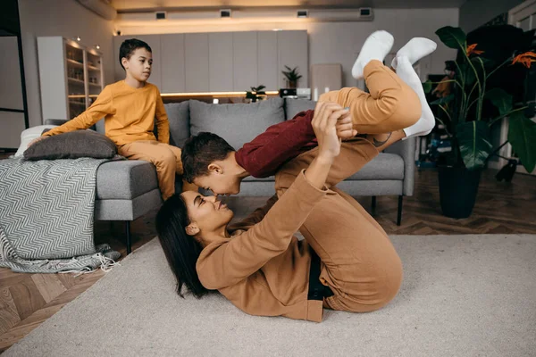 Mom teaches her two sons to do sports physical exercises in the morning at home