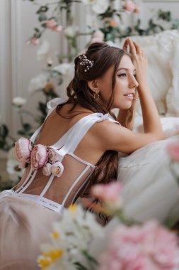 Bahar çiçekleriyle birlikte yatağın yanında pembe gelinlikli güzel kız.