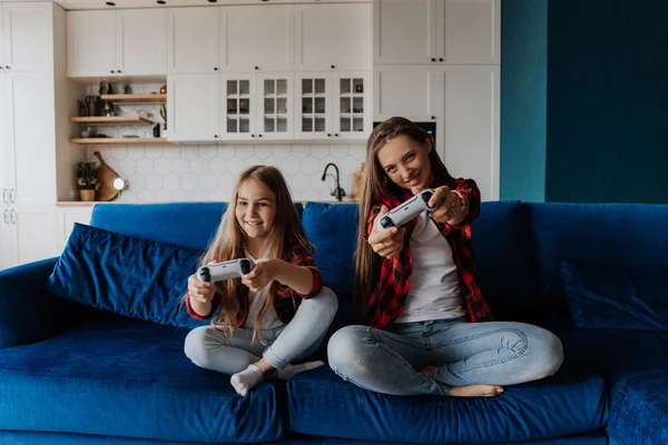 Dos hermanas en casa se divierten y juegan una consola con un joystick —  Fotos de Stock