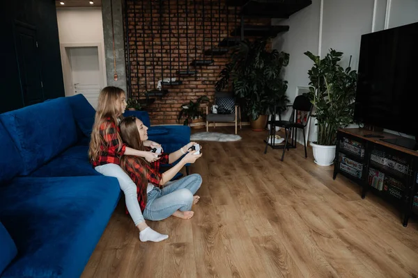 Dos hermanas en casa se divierten y juegan una consola con un joystick —  Fotos de Stock