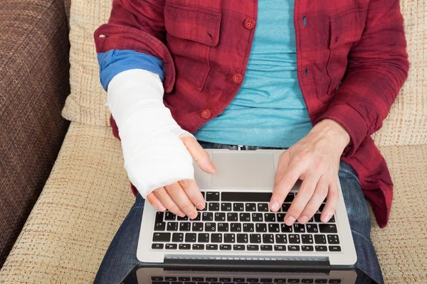 Arbetar på bärbar dator med skadade hand — Stockfoto