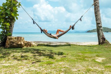 Siyah bikinili mutlu kadın hamakta dinleniyor.