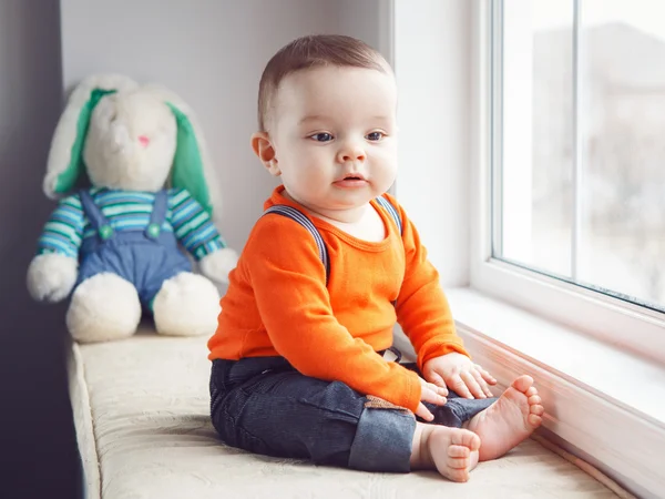 Portrait of cute adorable Caucasian baby boy sitting on windowsi — Stock Fotó