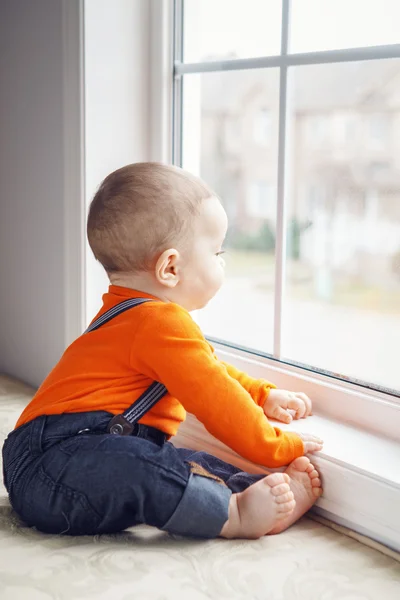 Porträt des niedlichen kaukasischen Jungen, der auf der Fensterbank sitzt — Stockfoto