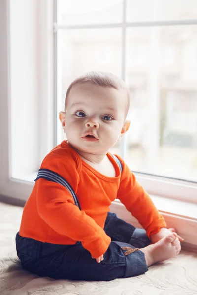 Portrait of cute adorable Caucasian baby boy sitting on windowsi — Stock Photo, Image