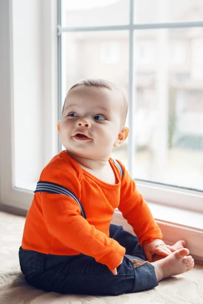 Portrait of cute adorable Caucasian baby boy sitting on windowsi — ストック写真