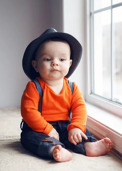 Bambino bambino carino in cappello vicino alla finestra — Foto Stock