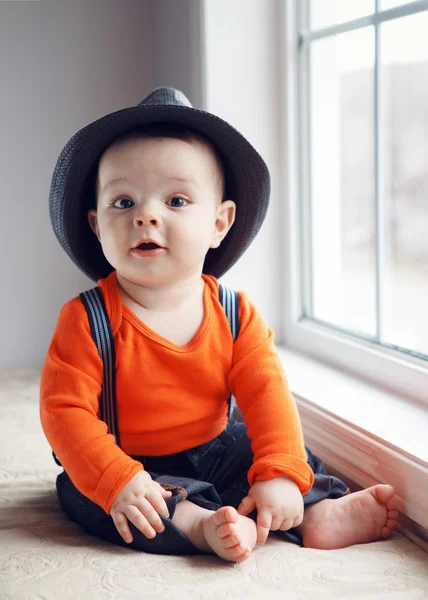 Cute infant baby in hat near window — Stock Photo, Image
