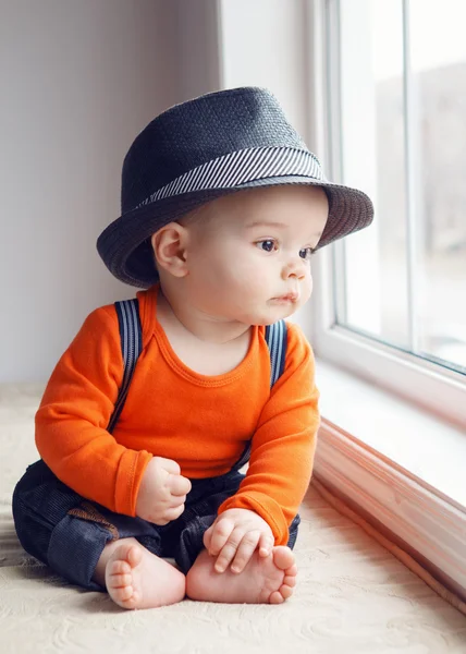 Bebê bebê bonito em chapéu perto da janela — Fotografia de Stock