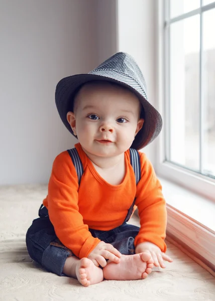 Cute infant baby in hat near window — Stock Photo, Image