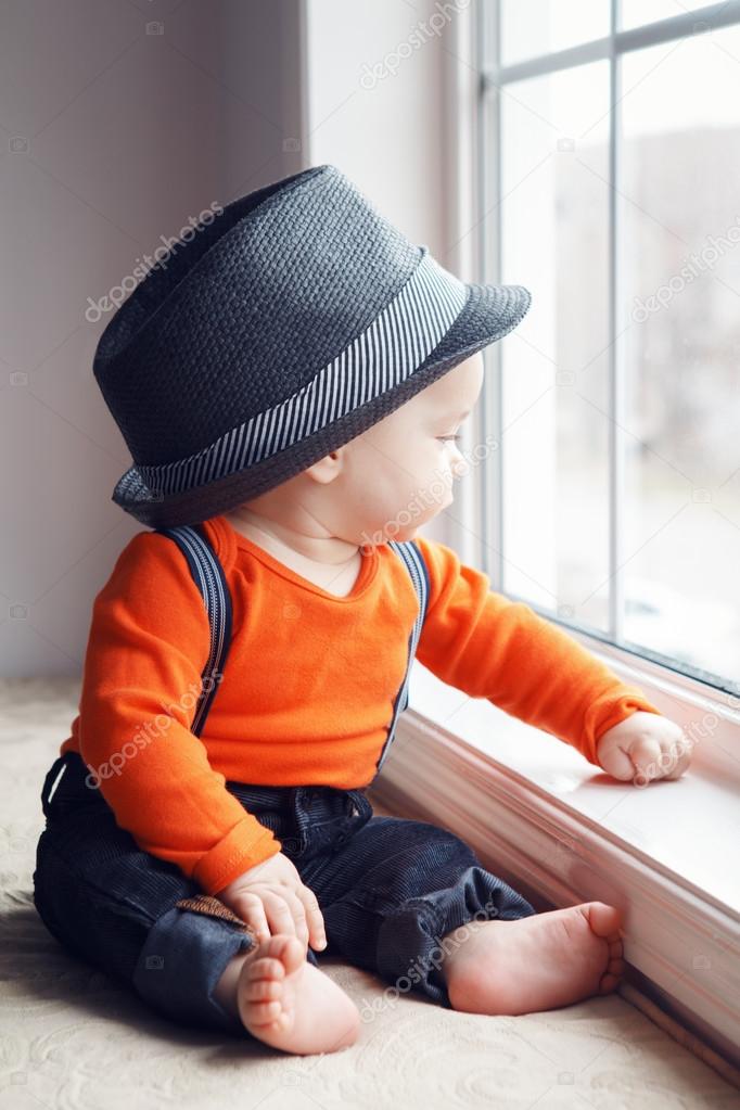 Cute infant baby in hat near window