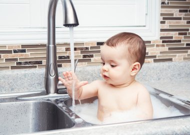 Oturan büyük evye su ve köpük, pencereden bakarak yakın yaşam tarzı her gün kavramı koyu siyah gözlü sevimli beyaz komik bebek kız çocuk portresi