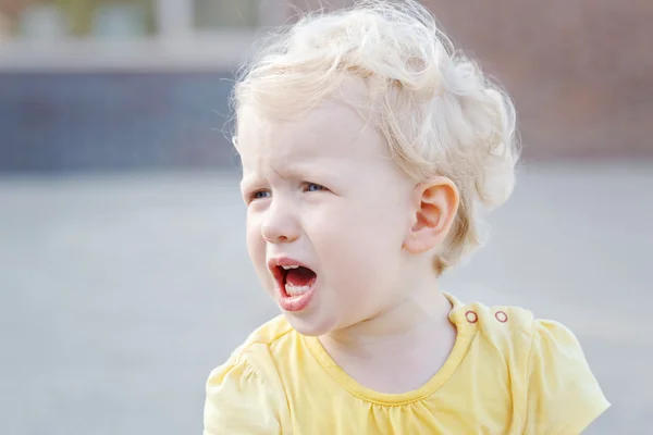 Close up ritratto di piangere urlando piccolo bianco biondo caucasico bambino ragazzo ragazza in abiti gialli fuori il giorno d'estate — Foto Stock