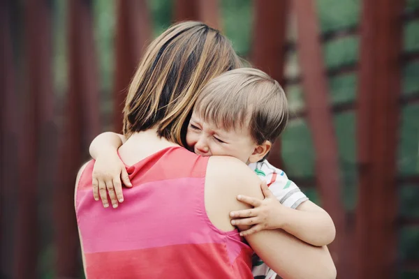 Retrato de la joven mujer caucásica madre consolando a su pequeño hijo llorando niño fuera en el parque en el día de verano, concepto de estilo de vida de la paternidad — Foto de Stock