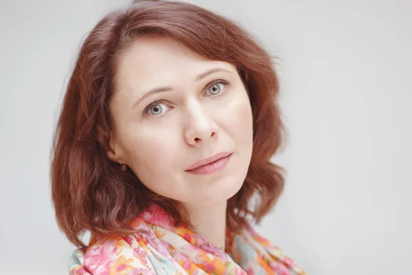 Closeup portrait of beautiful calm middle aged white caucasian brunette woman with green eyes covered with silk cotton scarf on her neck shoulders looking in camera on light white background — Φωτογραφία Αρχείου