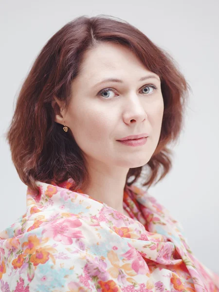 Closeup portrait of beautiful calm middle aged white caucasian brunette woman with green eyes covered with silk cotton scarf on her neck shoulders looking in camera on light white background — Φωτογραφία Αρχείου