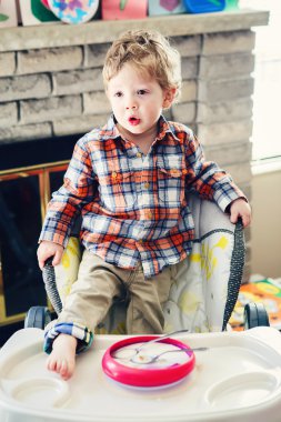 Sevimli sevimli Kafkas çocuk çocuk çocuk portre masanın üzerinde bacak ile yüksek sandalyede duran sabah erken, günlük yaşam tarzı samimi komik an, Instagram filtreleri ile tonda