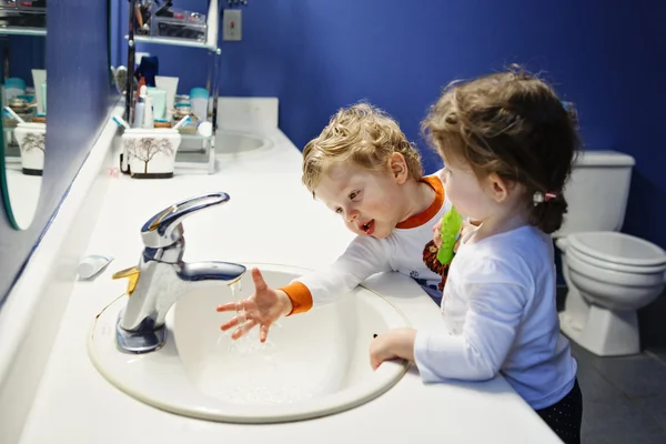 화장실 화장실 에서 쌍둥이 아이 유아 소년 소녀의 클로즈업 초상화 는 물과 함께 놀고 있는 이빨로 치아를 닦는 손, 라이프 스타일 홈 스타일, 일상 적인 순간, 아침 루틴 — 스톡 사진