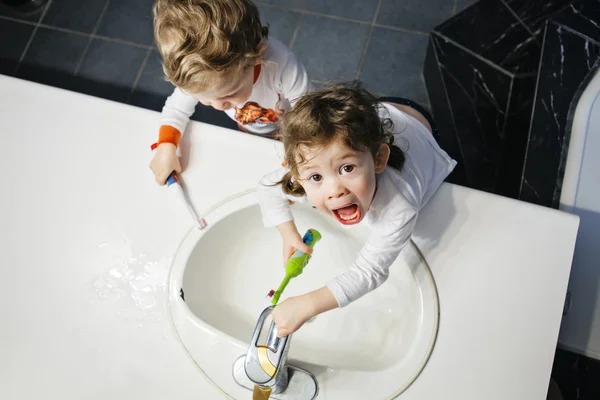 Zbliżenie portret bliźniaków dzieci Toddler chłopiec dziewczyna w łazience toaleta mycia twarzy ręce szczotkowanie zębów z toothbrash gry z wodą, styl życia domu, codzienne chwile, widok z góry — Zdjęcie stockowe