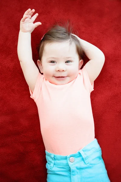 Retrato de linda adorable niña niño sonriente caucásica acostada en el suelo manta roja en la habitación de los niños mirando en la cámara, luz natural de la ventana, estilo de vida —  Fotos de Stock