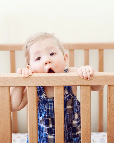 Porträt eines niedlichen entzückenden lustigen Babys von neun Monaten, das im Bett steht, Krippe kauend, Holzseiten lutschend, in die Kamera schauend, Lifestyle-Alltag süßer, ehrlicher Moment — Stockfoto