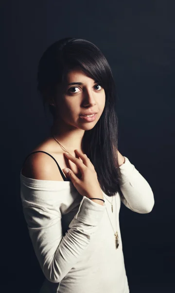 Portrait of beautiful Hispanic latino white girl woman with dark brown eyes, long dark hair in white shirt falling from her shoulder, showing bare skin bra, posing in studio on dark black background — Stock Photo, Image